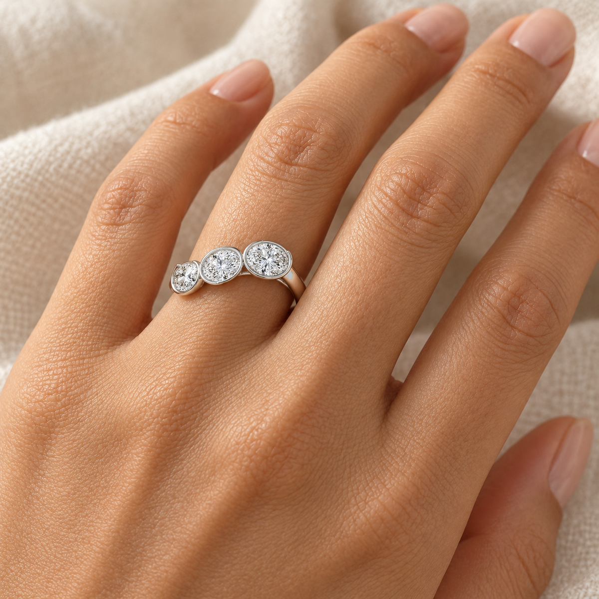 Oval Bezel Trio Ring in 14K white gold worn on hand – illustrative rendering, approximate scale